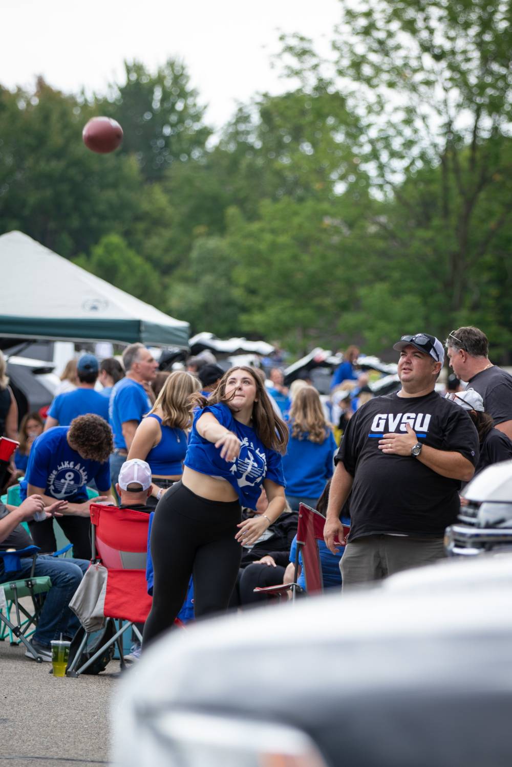 Attendee throws football in parking lot during Family Day tailgate.